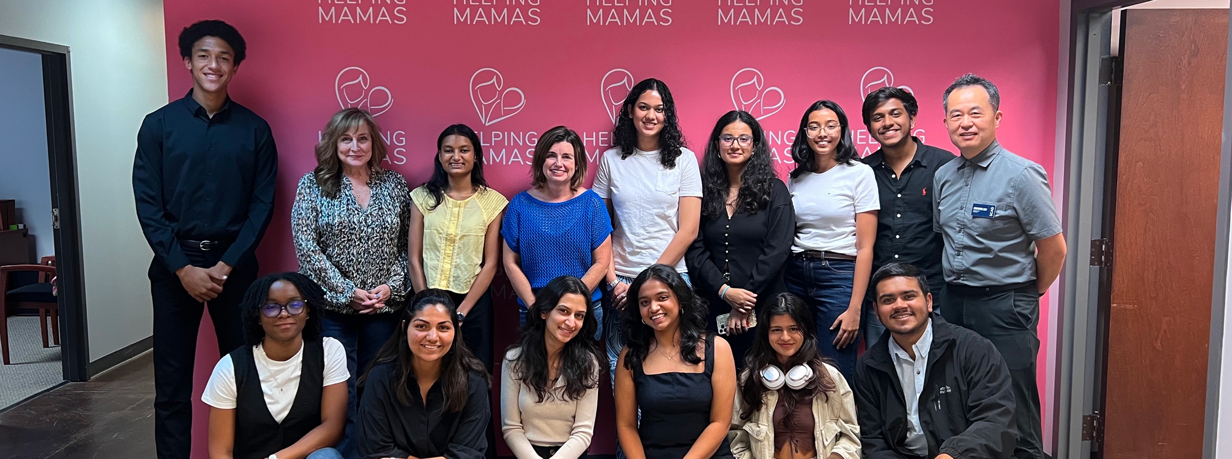 The SCADserve team with Helping Mamas, in front of the Helping Mamas wall.